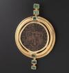 <span class='ref_item'>8 -</span>  <span class="object_title">COLGANTE EN ORO DE 18KT. CON ESMERALDAS Y MONEDA</span><br><span class="technical_description">Colgante realizado en oro de 18kt. con esmeraldas en su talla de diferentes tamaños con un peso total aprox 0.80ct. en el centro una moneda arqueologica.</span>  