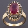 <span class='ref_item'>63 -</span>  <span class="object_title">SORTIJA EN ORO DE 18KT. CON RUBÍ Y ZAFIROS NEGROS </span><br><span class="technical_description"> Sortija realizada en oro de 18kt. con centro de rubí en talla oval de peso aprox 3.35ct. engastado por cuatro garras y orla de zafiros negros con un peso aprox de 0.55ct. </span>  