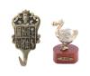 <span class='ref_item'>193 -</span> <span class="object_title">LOTE DE DOS OBJETOS EN METAL PLATEADO</span>   <p><span class="technical_description">Colgador en latón dorado repujado con escudo castellano. Medidas: 12,5cm<br/>Figura en metal dorado representando al pájaro DODO sobre base de madera. Medidas: 9cm</span><br></p>