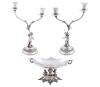 <span class='ref_item'>268 -</span> <span class="object_title">CONJUNTO DECORATIVO DE CANDELABROS Y FUENTE  CENTRAL  EN PLATA DE LEY 925 </span>  <p><span class="technical_description">Conjunto decorativo de dos candelabros y fuente central realizados en plata de ley 925<br/>Los candelabros de dos luces están decorados con detalles de querubines y motivos vegetales y la pieza central en forma de fuente o plato también presenta figuras ornamentales similares a los candelabros y base profusamente decorada con tornapuntas, rocalla y motivos vegetales<br/>Medidas candelabros: Longitud 40 cm de alto , y diámetro de base 13,3 cm. No llevan contrapeso<br/>Fuente: Longitud 17,5 cm x 36 cm de ancho x 18,5 cm de fondo<br/>Peso neto plata: 2.620 gr</span><br></p>